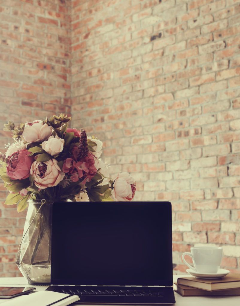 Computer with vase and brick wall