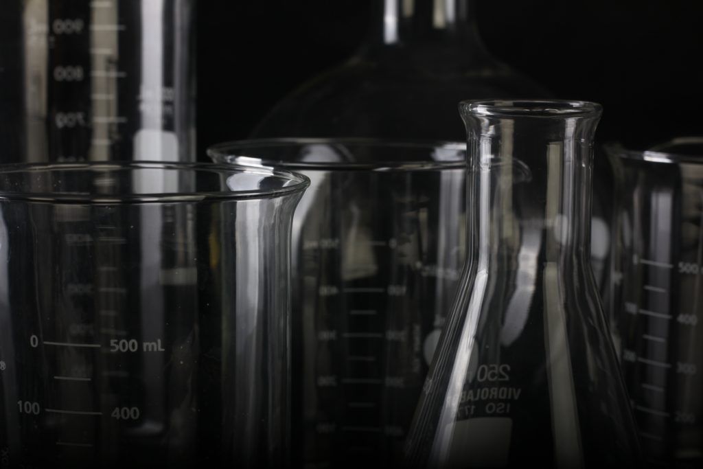 Imagen con probetas y pipetas de laboratorio de investigación, en blanco y negro, con escala de grises