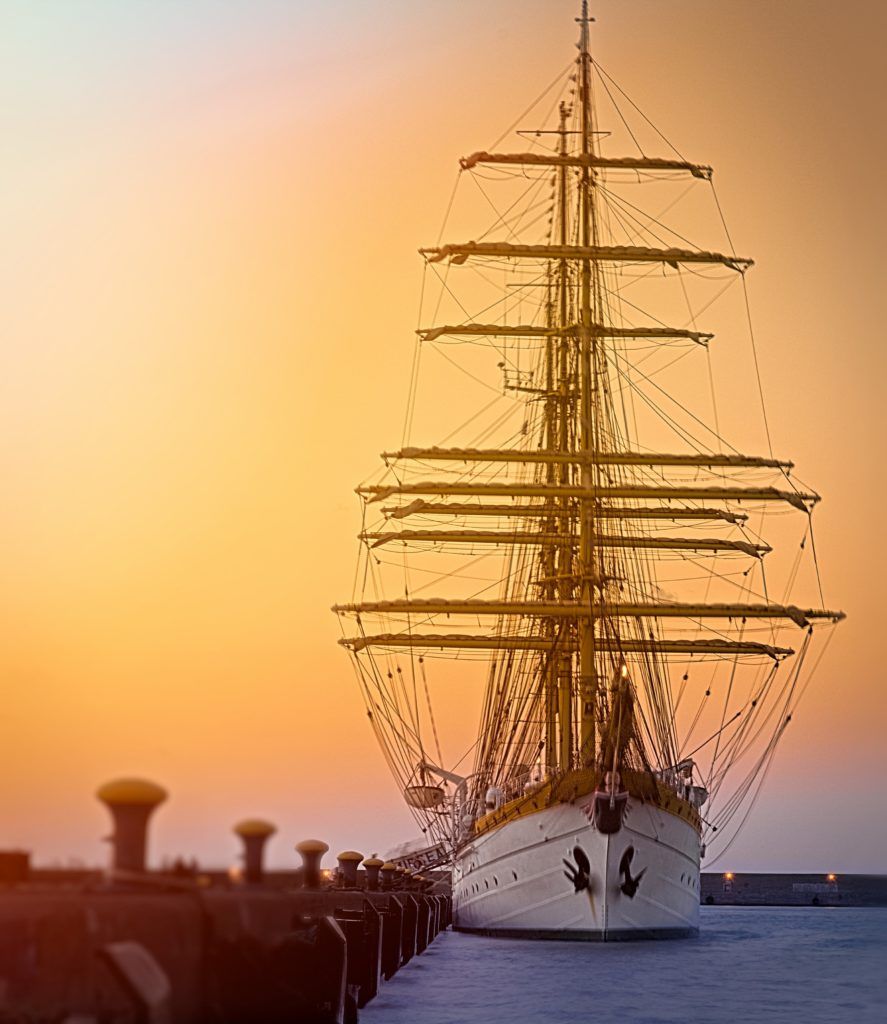 Vista de buque de vela con las velas arriadas con puesta de sol
